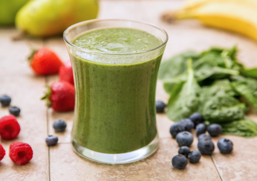 green smoothie with strawberries, bananas and kale on wooden table