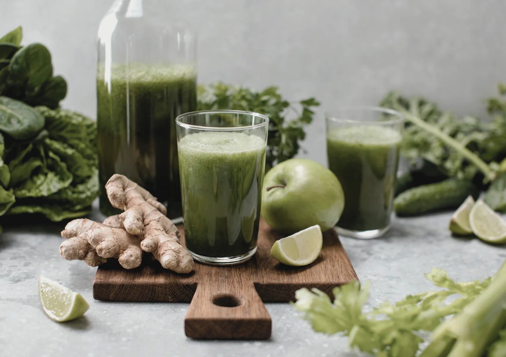 green smoothie with ginger and vegetables on wooden tray