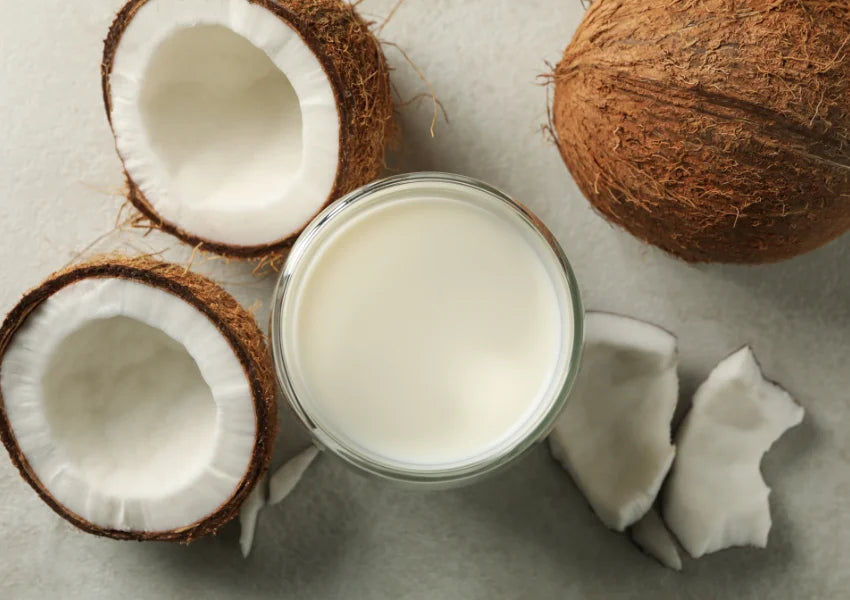 coconut milk in a glass surrounded by coconut husks and coconut flesh