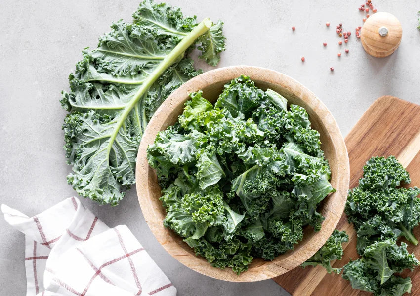 kale leaves in a wooden bowl and wooden tray on table
