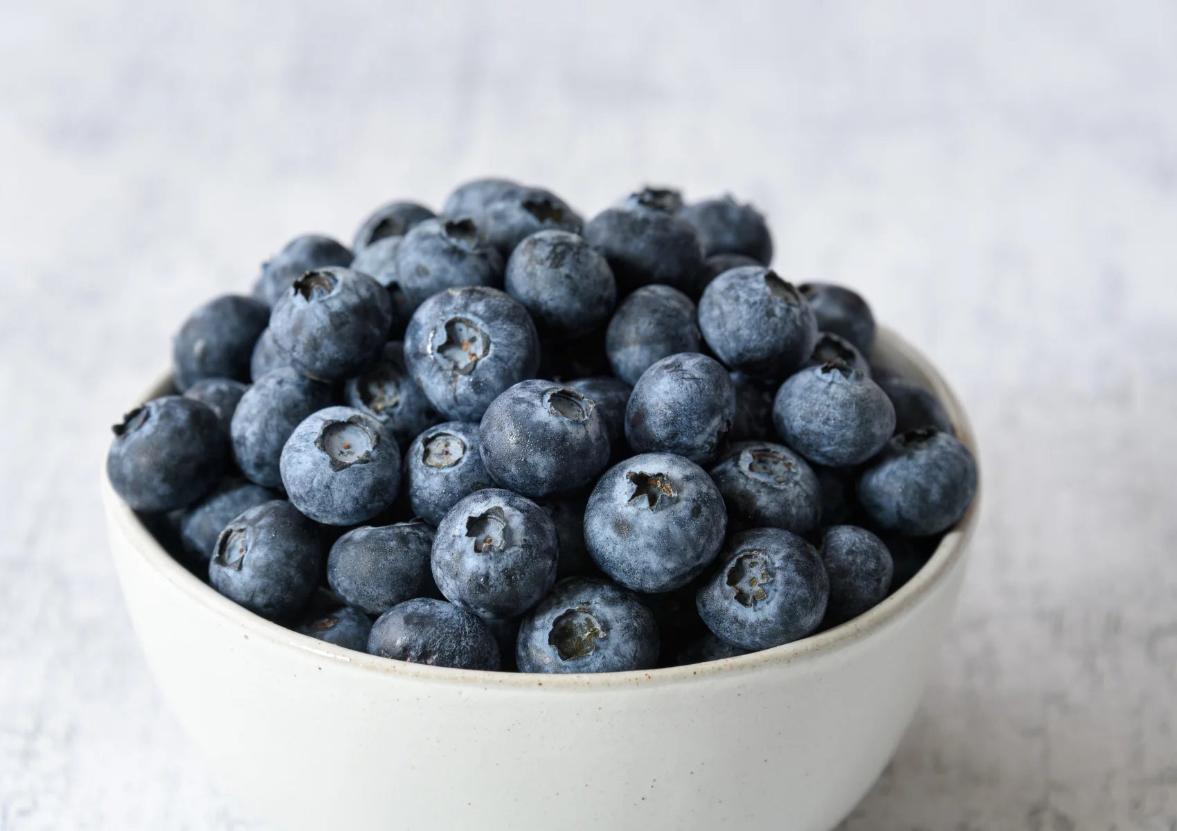 blueberries in a white bowl on wooden table