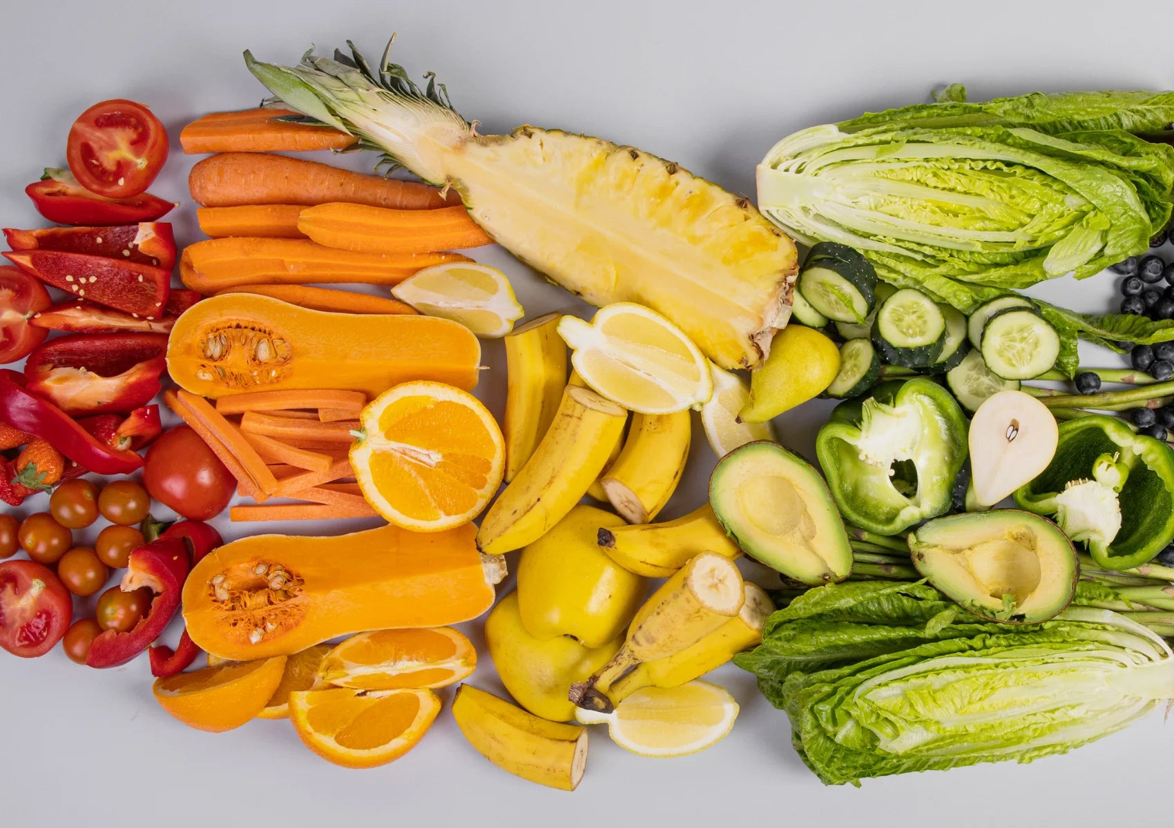 two portions of fruits with tomatoes, carrots, pineapples, bananas, lemons, kiwi, avocado. one portion of vegetables with lettuce, cucumbers