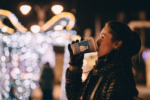 Person enjoying a warm beverage during holiday season, exuding a cozy and festive atmosphere.