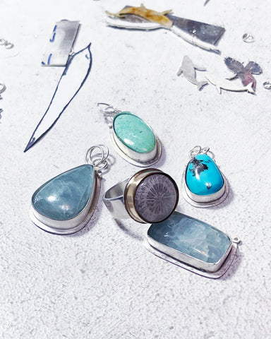 In process jewelry with blue and green stones on a white background