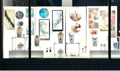 Window display for May 2023 at Artistic Portland Gallery showing paintings in the back, with jewelry by Catherine Chandler and Heather John in the foreground