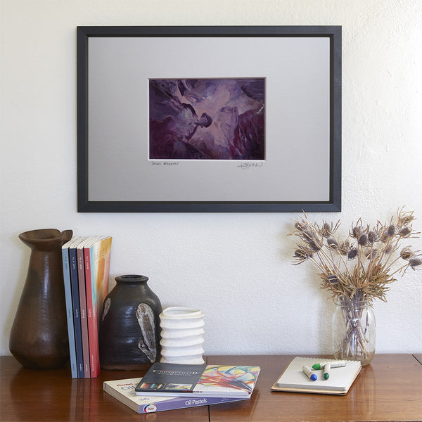 Kimberli Werner Art, Small Wonders, original monotype, encaustic wax, shades of purple, artwork on the wall behind a desk containing vases, books, and a dried plant.