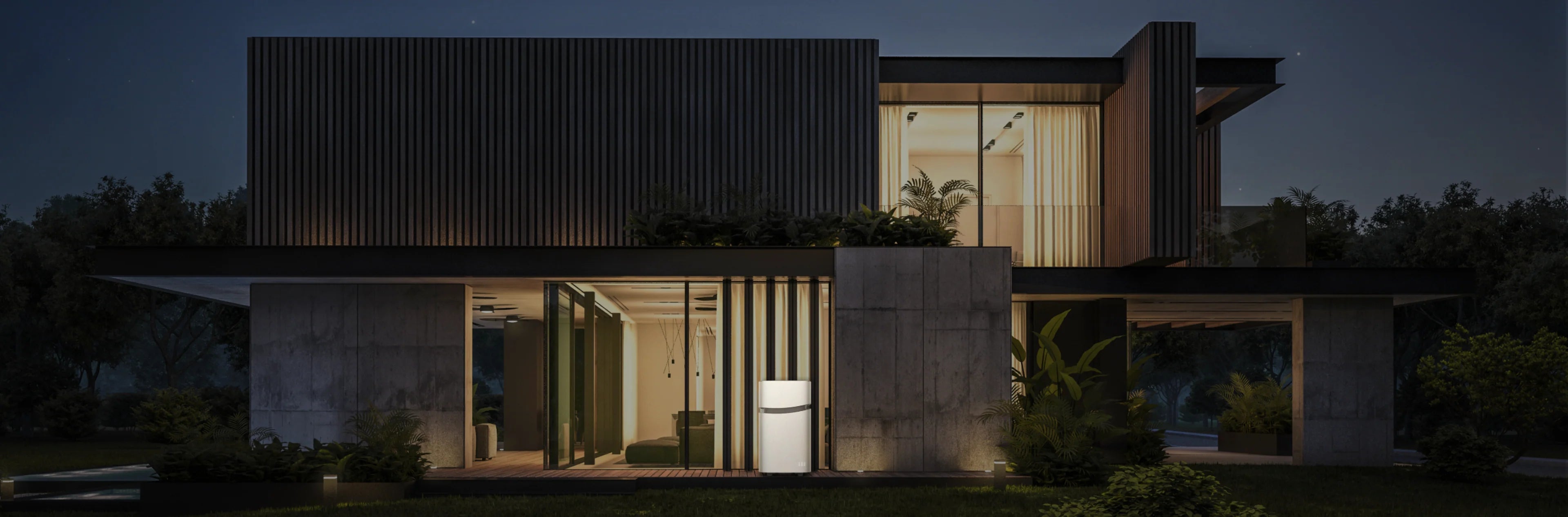 Modern two-story house at night with large glass windows and concrete walls, warmly lit and surrounded by greenery. The home stays powered and secure using the Mango Power 4,350W 6,900Wh Union Portable Battery and Power Station from Mango Power.