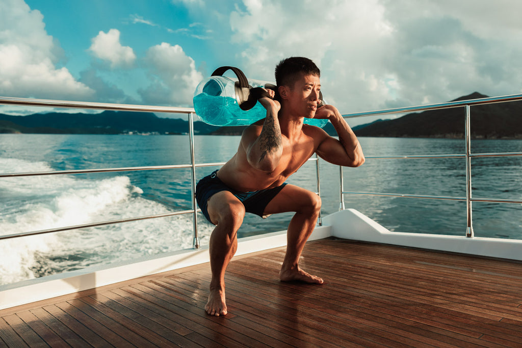 A man squatting down with FluidX's tank aqua bag over his shoulders - FluidX