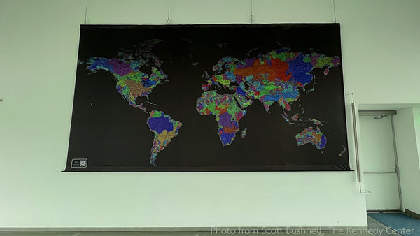 A picture of Grasshopper Geography's river basin map of the world hung from the ceiling in a spacious room.