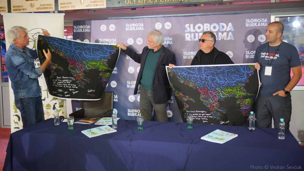 Conférence de presse Freedom for the Rivers : Ulrich Eichelmann distribue deux cartes fluviales Grasshopper Geography des Balkans à des musiciens locaux en guise de cadeau de remerciement.