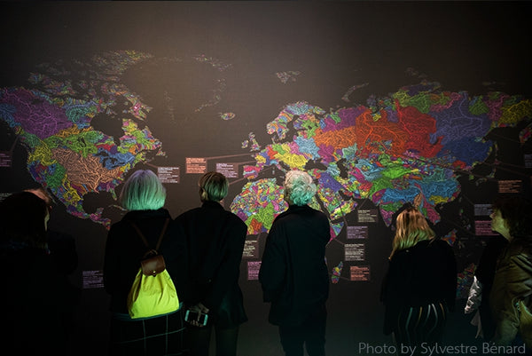 People standing in front of Grasshopper Geography's giant river basin map at the Nous, les Fleuves exhibition in the Musée des Confluences. 