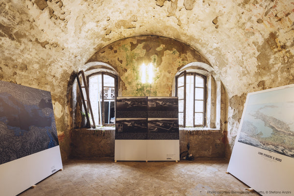 Photo montrant une pièce du fort avec trois panneaux adossés aux murs. Les murs sont nus et il y a à la fois de la lumière naturelle provenant des fenêtres et une lampe suspendue au plafond. L'œuvre d'art de gauche est la carte des bassins fluviaux de la Méditerranée de Grasshopper Geography qui a été soumise à la Biennale dello Stretto en 2022.