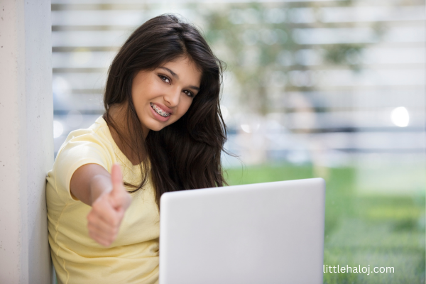 Teen giving thumbs up while working on computer