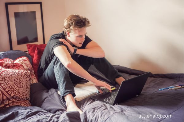 Teen guy on his bed looking at laptop