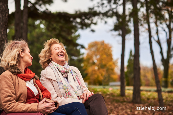 2 senior ladies on park bench laughing at jokes
