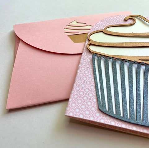 a handmade cupcake card lays on top of a handmake pink envelope with cupcake detail on the flap