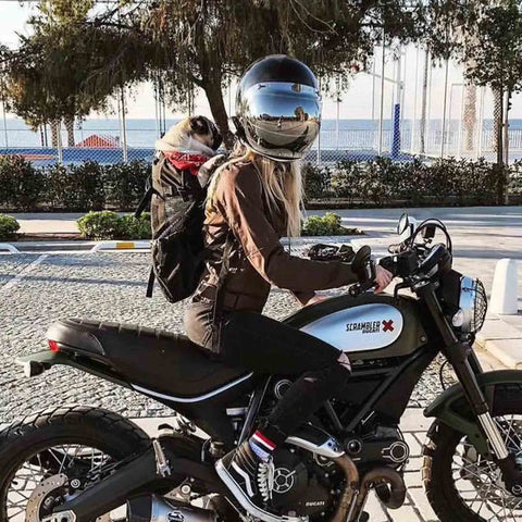 woman on motorcycle wearing a dog carrier backpack