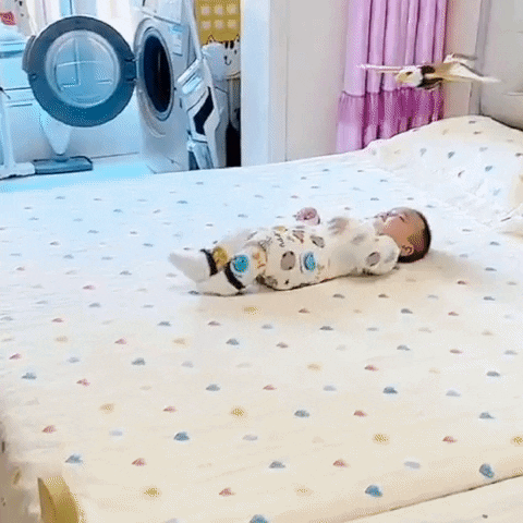 baby on bed playing with flying bird toy