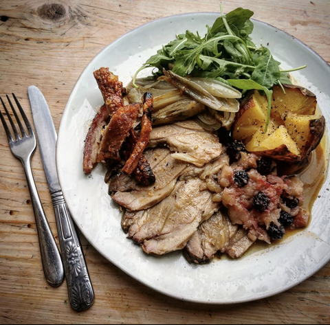 Plate of roast pork blade with apple and blackberry sauce and jacket potato