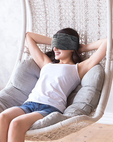 women asleep on chair with sleep headphones