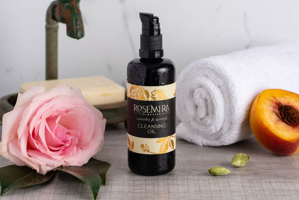 Camellia and Apricot Cleansing Oil with a pink rose, apricot, and a towel.