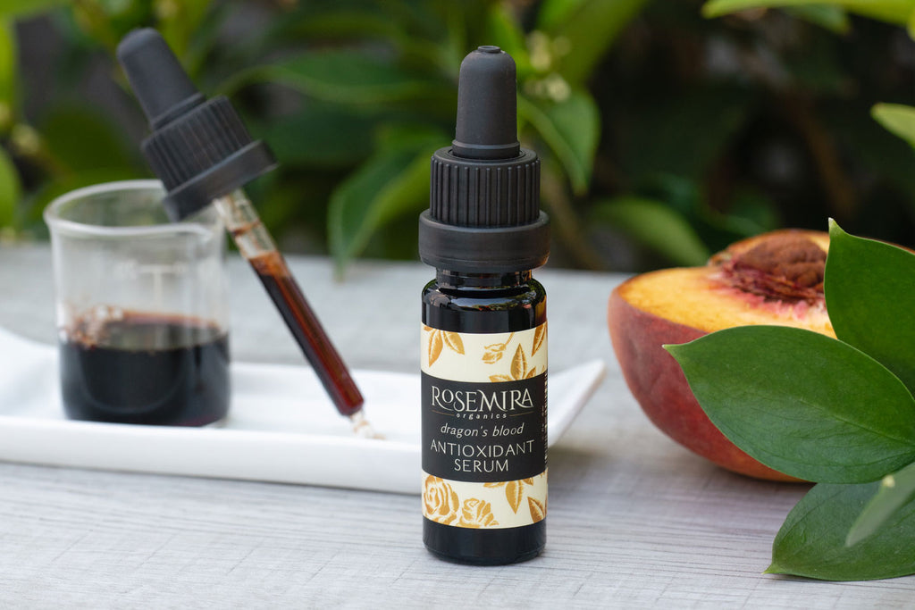 Rosemira Dragon's Blood Antioxidant Serum with a peach and a beaker of serum