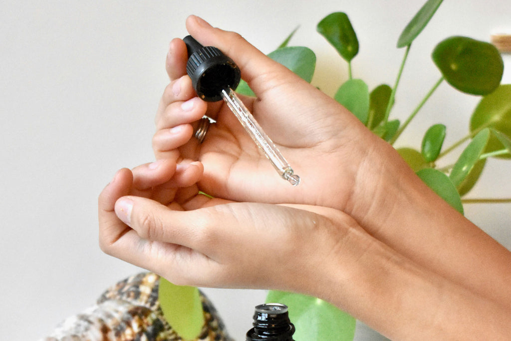 Caucasian hands holding a serum dropper