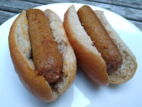 ic: Beyond Sausage_ hecho por Beyond Meat. Dos salchichas veganas, cocinadas en aceite de canola y servidas en panes para perros calientes.