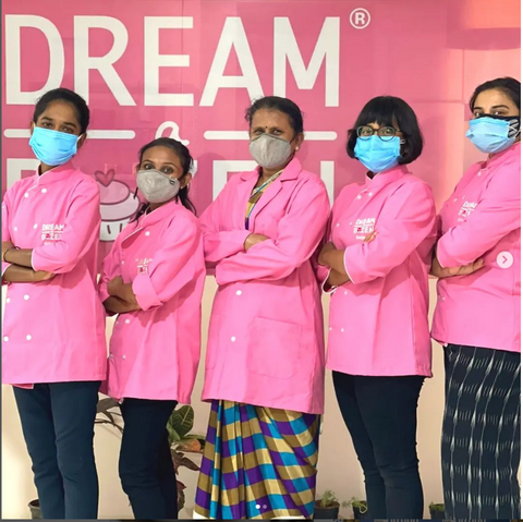 Five chefs from the kitchen wearing Dream a Dozen apron and posing for the camera in masks