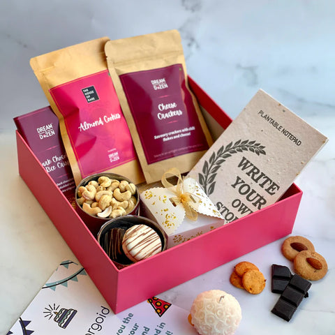 Daity Delight Box from the website containing packets of dry fruits, gourmet chocolates, handmade scented candle, cashews, plantable notebooks and reusable cardboard box