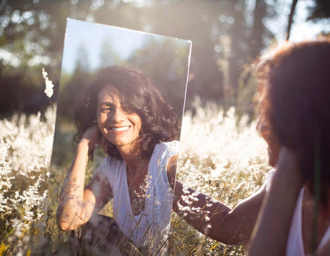 Frau im Blumenfeld mit Spiegel für BIOTURA Cleantech Beauty