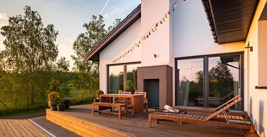 This wooden outdoor patio with wood furniture is highlighted by the sunset, bringing out rich earthy tones.