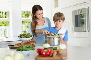 Mother and son (6-7) preparing food in kitchen