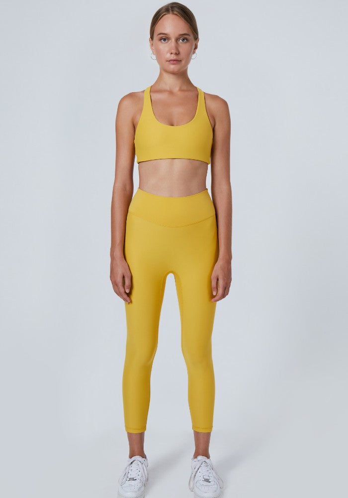 Front view of a woman wearing the Mila Leggings Mustard by Outfyt color Yellow made with ECONYLu00ae regenerated nylon