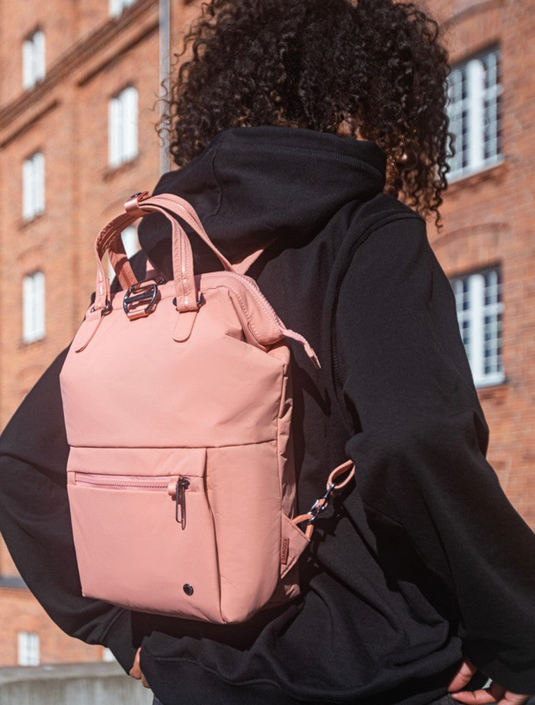 Woman travelling with the Pacsafe Citysafe CX Anti-Theft Mini Backpack color Rose made with ECONYLu00ae regenerated nylon