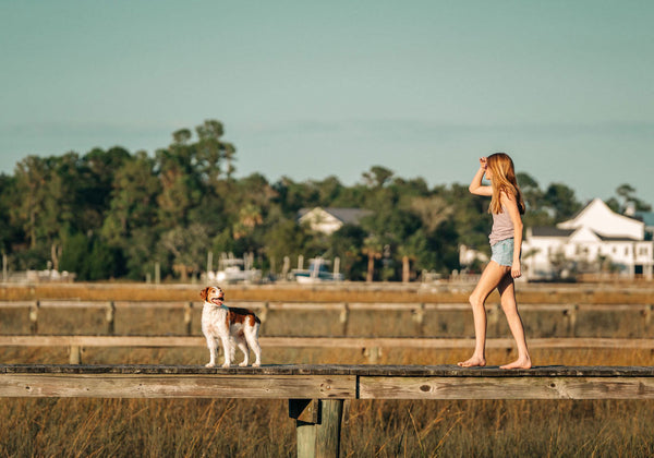 girl walking on the dock with a dog in front of her - How To Find Your Best Bralette Fit