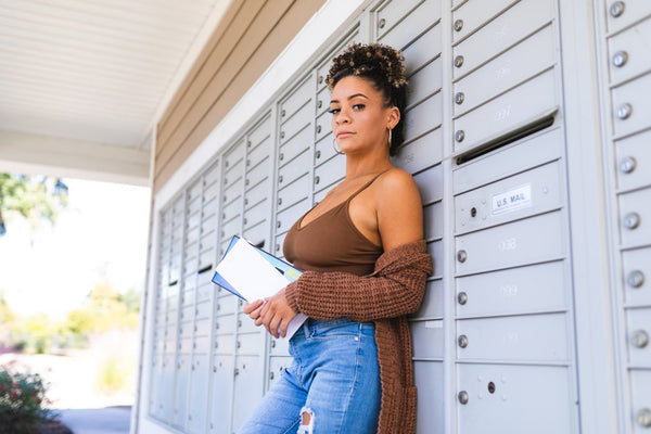 woman standing by mailboxes in a bra that conceals nipple piercings
