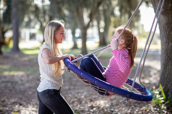 teenager pushing a tween in a swing - best training bras