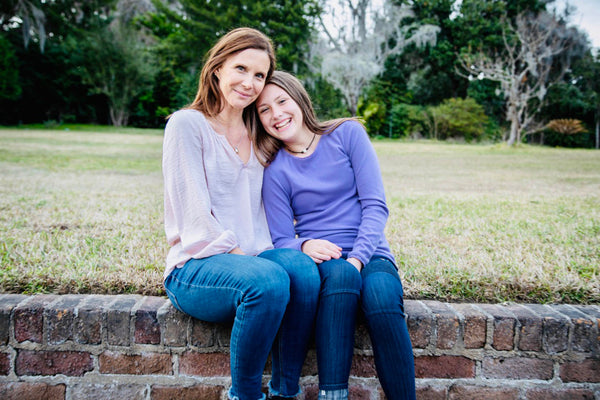 mom and her daughter sitting side by side smiling