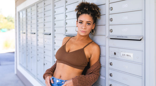 girl looking at camera by mailboxes in nipple concealing bralette by non disclosure apparel