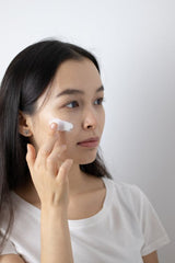 A woman applying moisturizer on her face