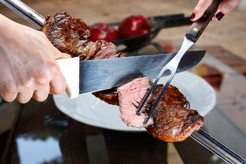 The roasted picanha is carved off the skewer, sliced thin.