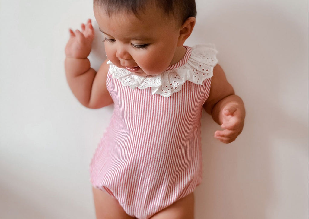 Baby wearing an organic cotton striped bubble romper from Lilly + Sid to keep cool in hot weather