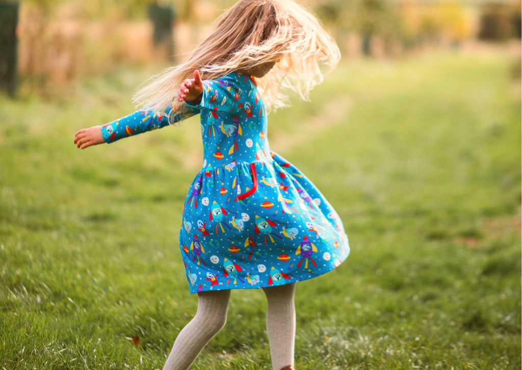 Girl playing outside in organic cotton dress by Ducky Zebra