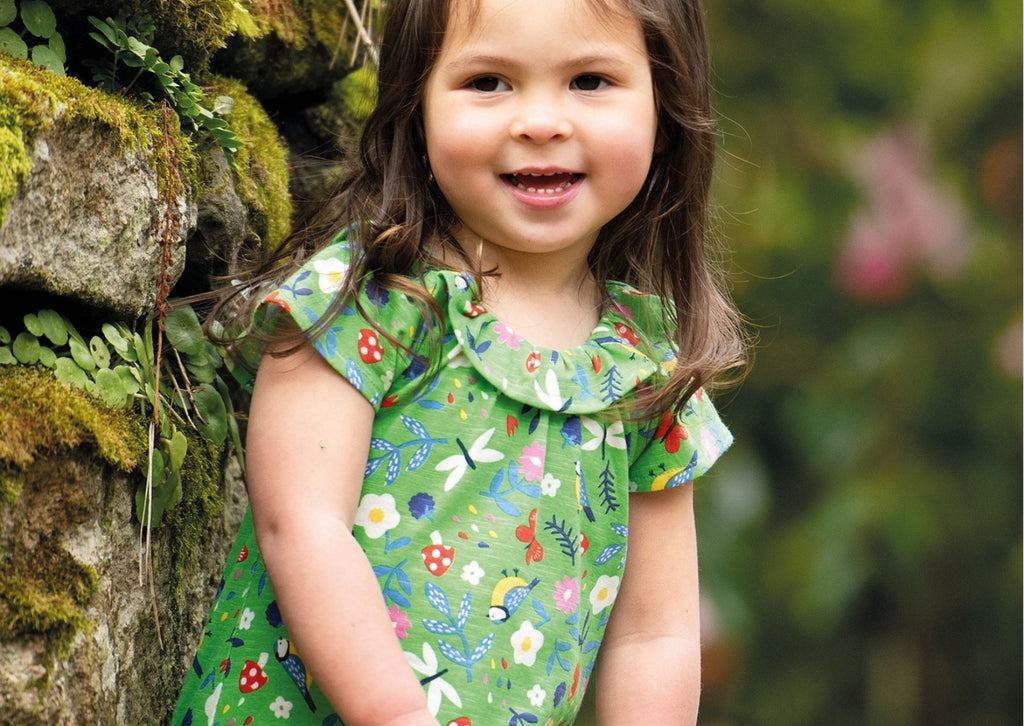 Best sustainable baby brand: Little girl wearing Frugi Esther playsuit