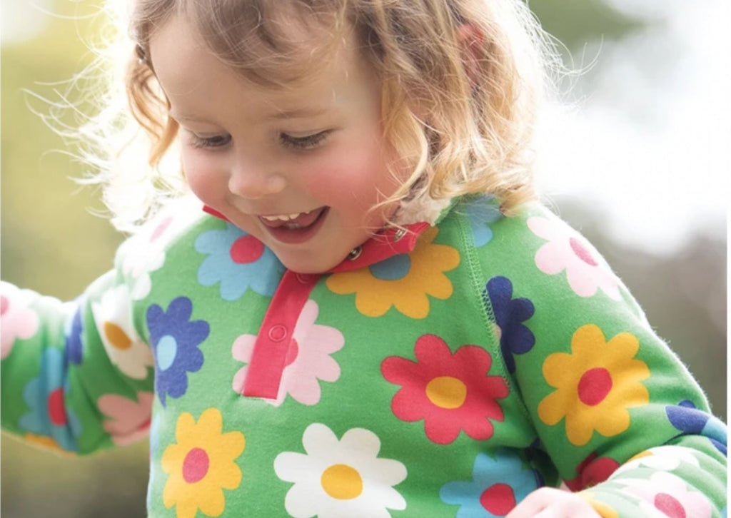 A little girl wearing a green floral Frugi Snuggle Fleece