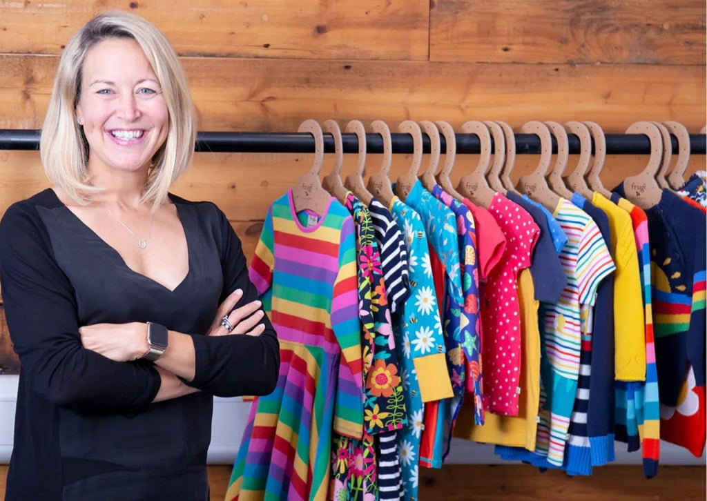 Sarah Clark, CEO of Frugi, stood next to a clothes rail of Frugi garments