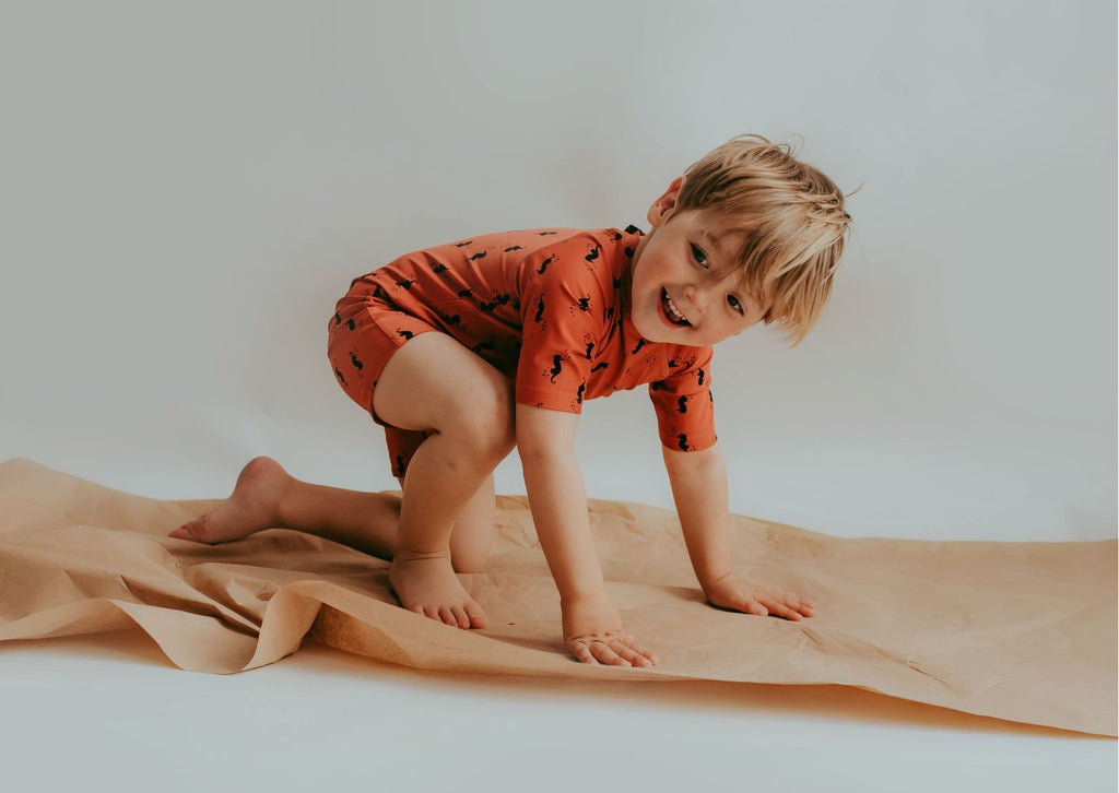 A little boy wearing a Turtledove surfsuit