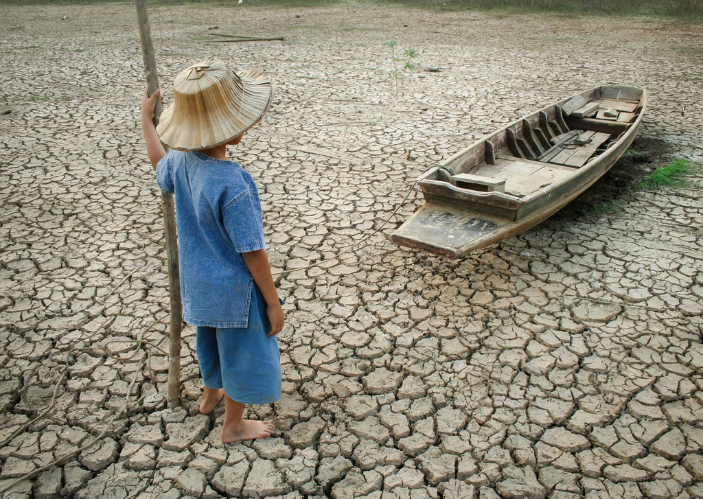 boy looking a dinghy resting on parched earth