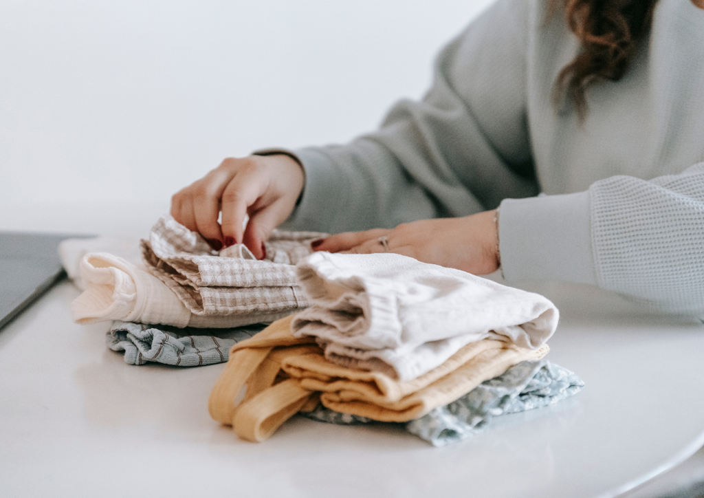 Mother sat with pile of baby clothes